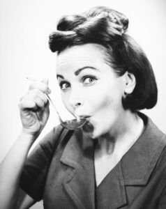 A woman tasting from a spoon.